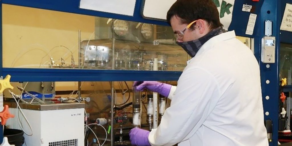 Aaron Salgado, a DEVCOM CBC chemist, places a tube containing a layer of carbon from the second source into a testing system that will analyze the time it would take a chemical agent to break through it (U.S. Army).