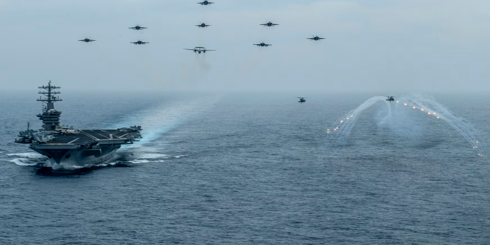PNG200602-N-VW723-1417 One naval vessel and eleven aircraft traveling over a body of water.