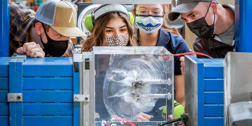 LITTLE BANG — From left, Joseph Pope, a Sandia technologist, Sivanna Torres, a New Mexico Institute of Mining and Technology doctoral student, Veronica Espinoza, a New Mexico Tech student, and Eric Robey, a Sandia mechanical engineer, examine a plexiglass cube fractured by a small-scale explosion. This study could inform the creation of new geothermal energy systems (photo by Bret Latter/Sandia National Laboratories).